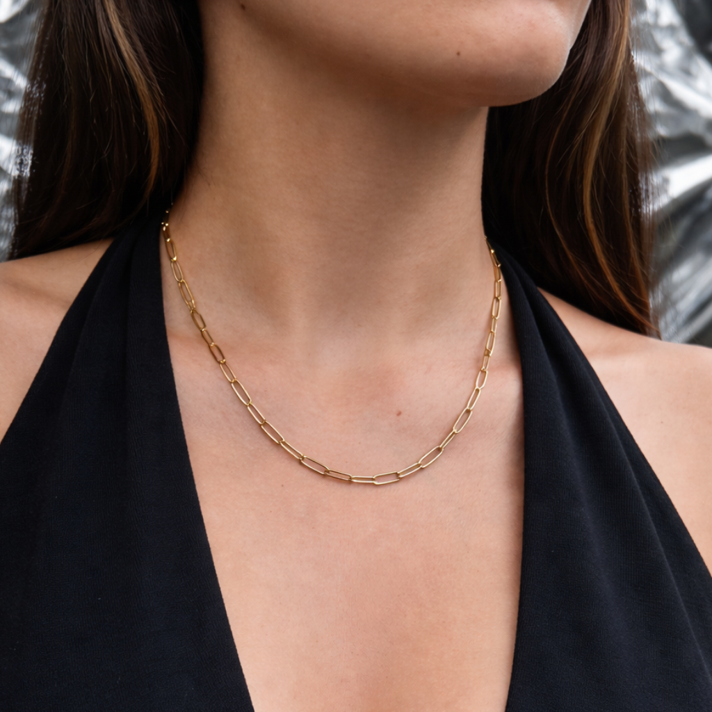 Collar de acero quirúrgico dorado con cadena de eslabones finos de 49 cm, usado en el cuello con outfit negro elegante.