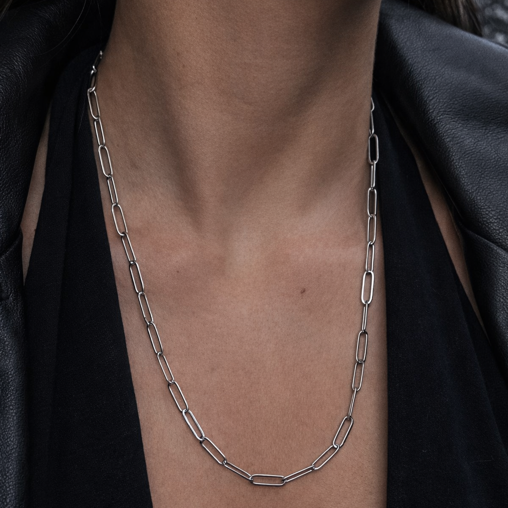 Collar de acero quirúrgico plateado con cadena de eslabones alargados de 54 cm, usado en el cuello con outfit negro minimalista.